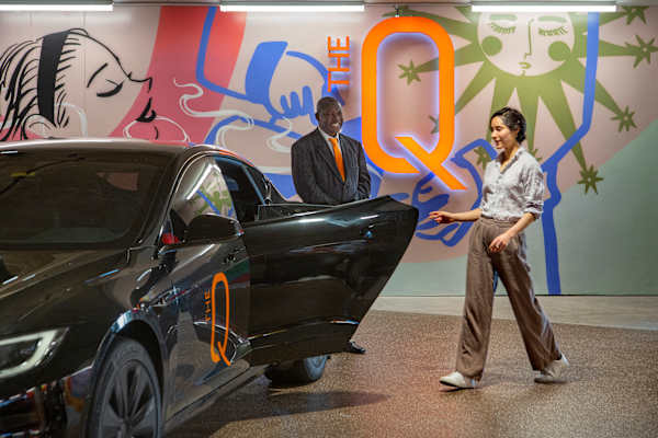 a man and a woman standing next to a black car